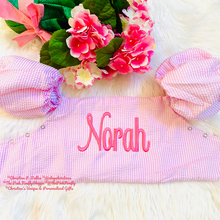 Load image into Gallery viewer, Pink baby puddle jumper cover with 'Norah' embroidered on it, surrounded by pink flowers and ribbons on a white background.